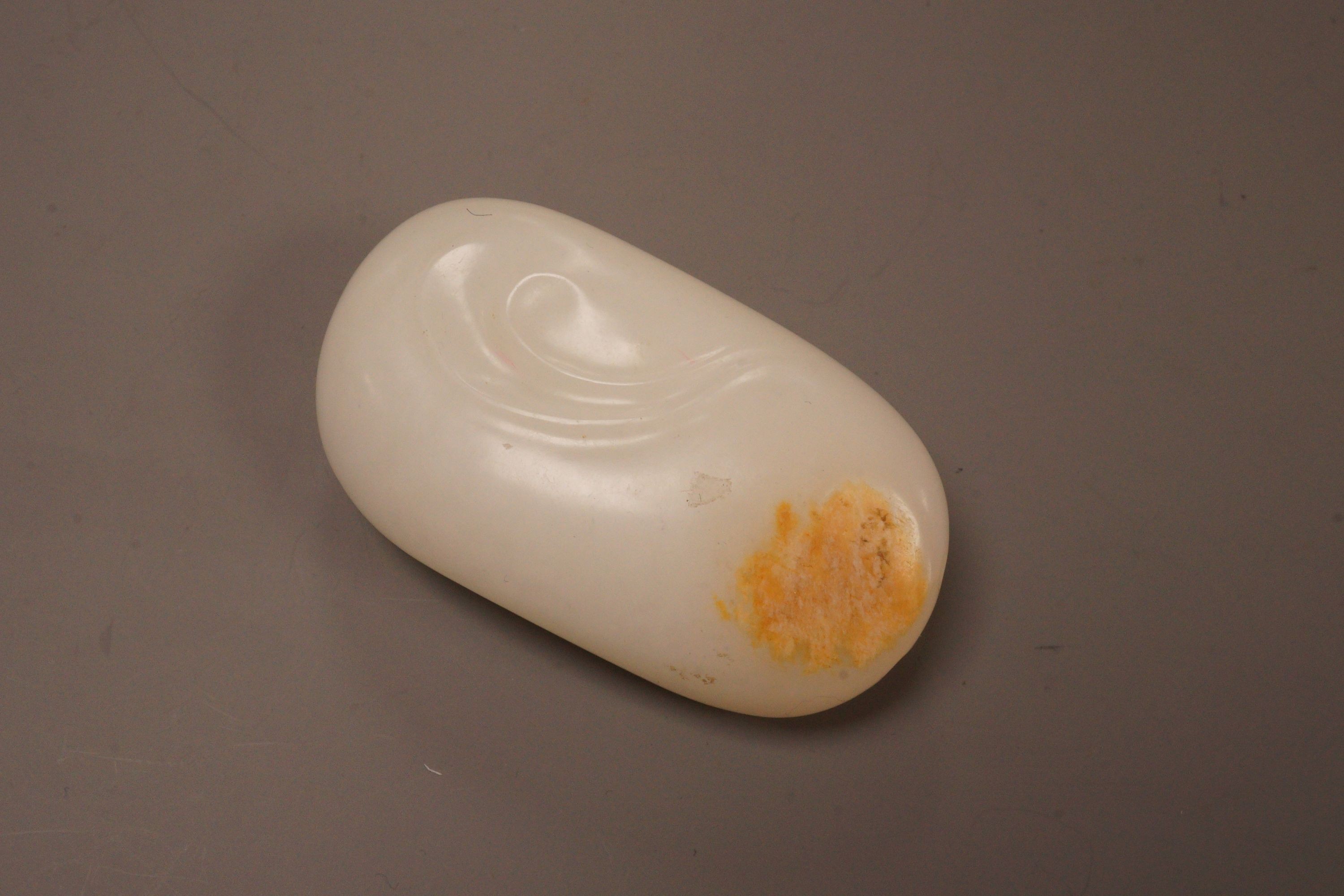 A Chinese white and russet jade pebble